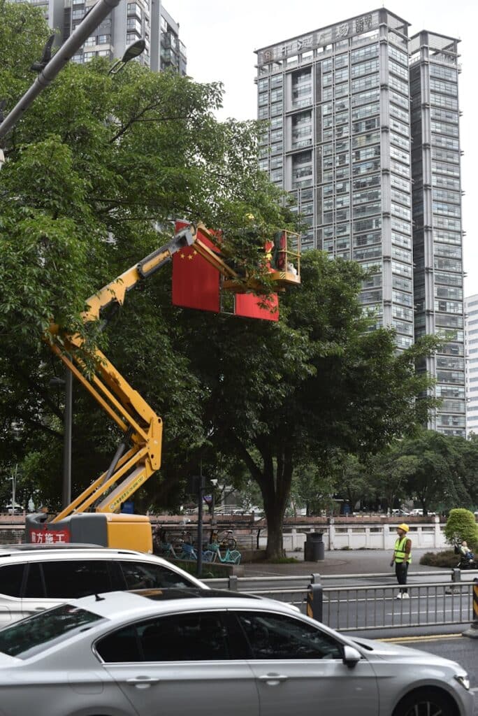 Cherry picker trimming trees with buildings behind.